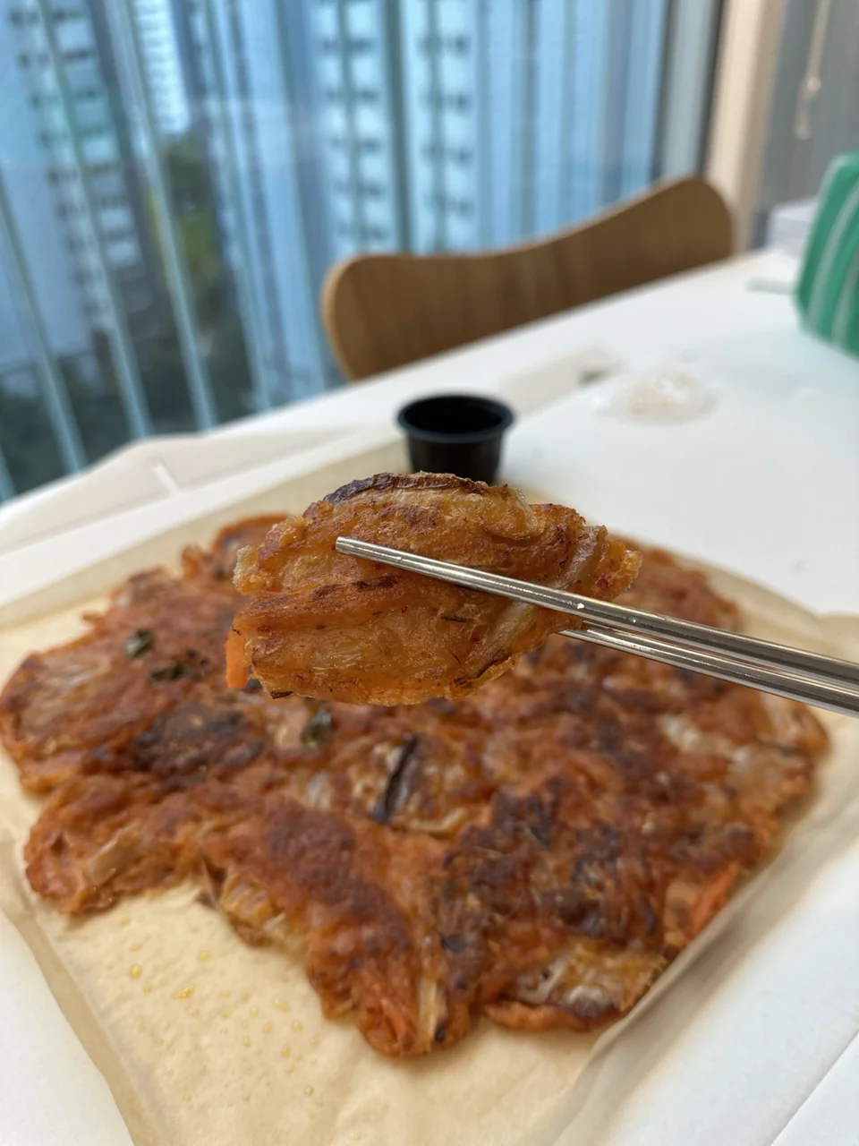 젓가락으로 들어 올린 김치전과 큼직한 김치