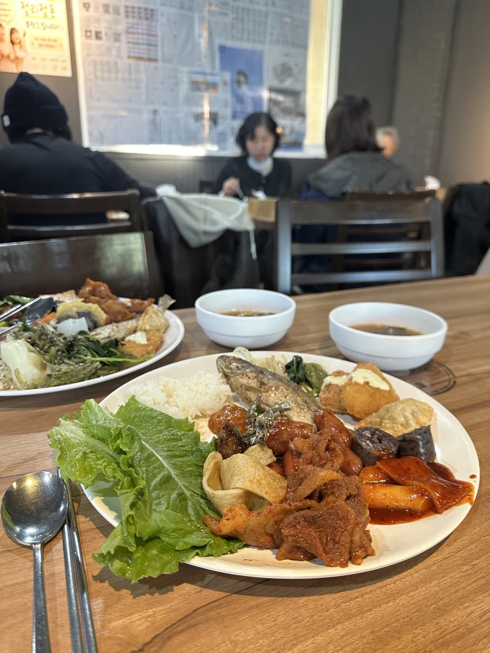 제육볶음과 떡볶이 등 여러 음식을 담은 접시와 국